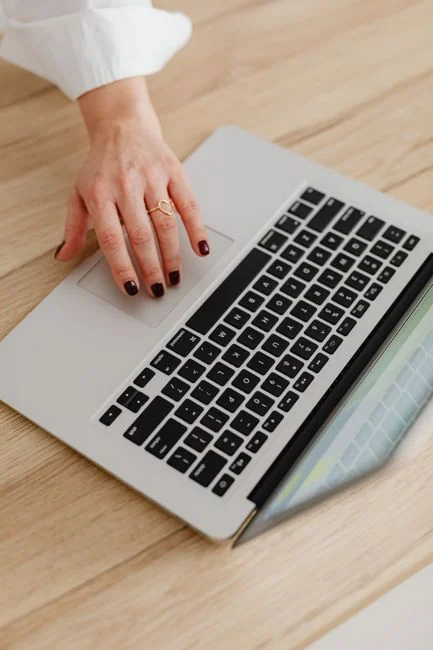 A man is using a laptop indoors to examine a stock market trend graph displayed on the screen.